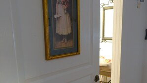 Un pasillo con un retrato enmarcado en la pared, una puerta que da al baño y piso de madera.