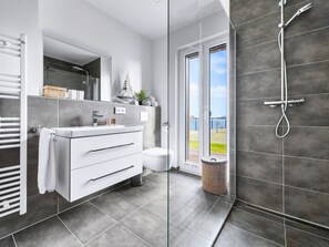 A modern bathroom with a glass shower enclosure, a white vanity, and a view of the outdoors. - Admiralslounge- EG, Infrarotsauna, Grosse Dusche, Terrasse, Blick auf das Hafenbecken (Olpenitz)