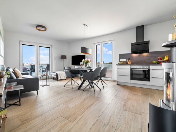 A modern apartment with a dining area, kitchen, and a balcony with a city view.