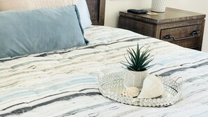 A neatly made bed with a patterned bedspread, a decorative tray with a plant and seashells, and a bedside table with a lamp and remote control. - Luxury Retreat/Heated Pool/2Kings /n.Beach/Office (Rotonda West)