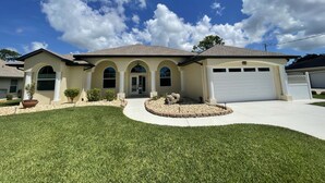 A two-story house with a garage, a driveway, and a well-maintained lawn. - Luxury Retreat/Heated Pool/2Kings /n.Beach/Office (Rotonda West)