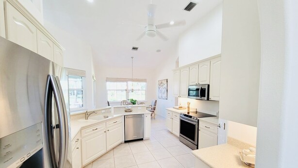 A modern kitchen with white cabinetry, stainless steel appliances, and a large window providing natural light. - Luxury Retreat/Heated Pool/2Kings /n.Beach/Office (Rotonda West)