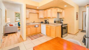 A compact kitchen with wooden cabinets, a dishwasher, a stove, and a refrigerator. - Updated Downtown Home w/ Garage & WiFi (Appleton)