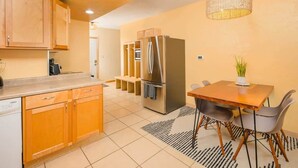 A modern kitchen with wooden cabinets, stainless steel appliances, and a dining area with a table and chairs. - Updated Downtown Home w/ Garage & WiFi (Appleton)