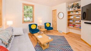 A cozy living room with a sofa, two blue armchairs, a wooden coffee table, and a TV on the wall. - Updated Downtown Home w/ Garage & WiFi (Appleton)