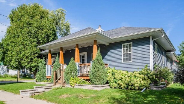 A two-story house with a front porch, a covered entryway, and a well-maintained lawn. - Updated Downtown Home w/ Garage & WiFi (Appleton)