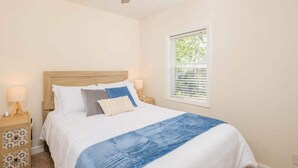 A bedroom with a bed, a nightstand, a lamp, a ceiling fan, and a window with blinds. - Updated Downtown Home w/ Garage & WiFi (Appleton)