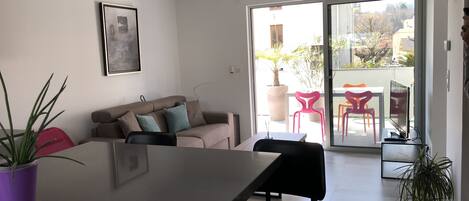 Un espacio moderno para vivir con comedor, un sofá y un ventanal corredero que da a un patio exterior.
