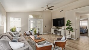 A living room with a sofa, chairs, a coffee table, a TV, and a ceiling fan. - Gilbert Luxury Remodel ~ EV Charger, 1-Level Comfort, Family & Pet-Friendly (Gilbert)