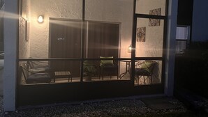 A modern house with a large glass door leading to a patio area with outdoor furniture. - Centrally located Condo, Sarasota Fl 34232 (Sarasota)
