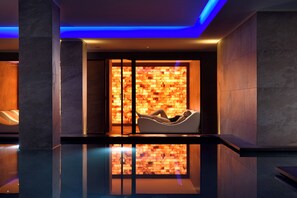 A spa room with a massage chair, a wall with a warm-toned mosaic, and a reflective floor. - Valtur Cervinia Cristallo Ski Resort (Valtournenche)