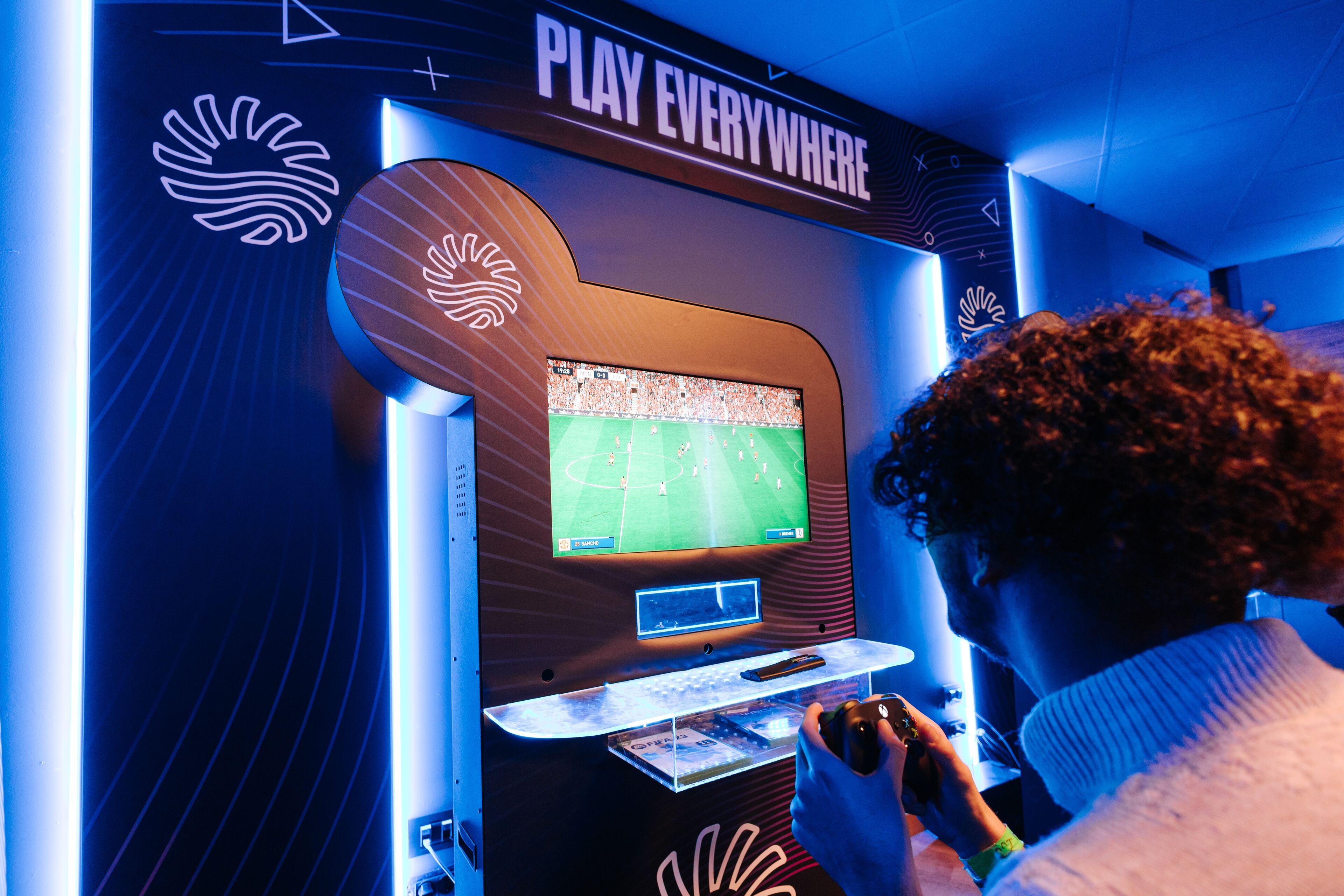 Una persona juega un videojuego de fútbol en una sala de juegos.