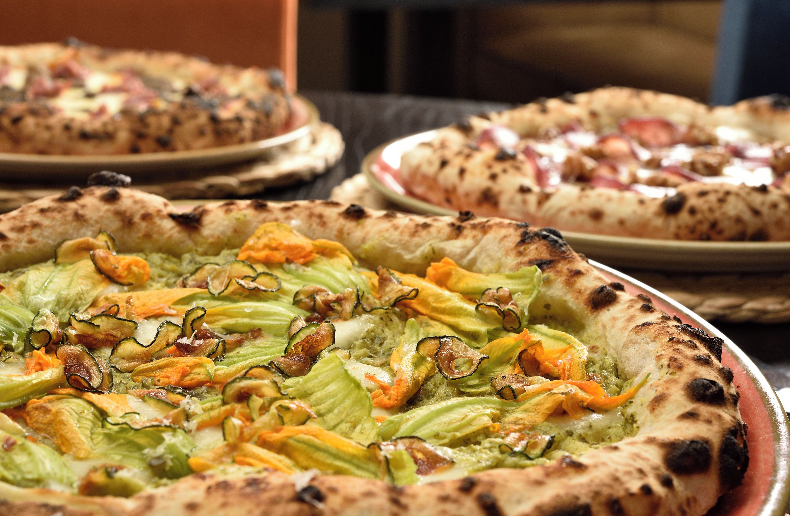 Verschiedene Pizzen mit unterschiedlichen Belägen auf einem Tisch.