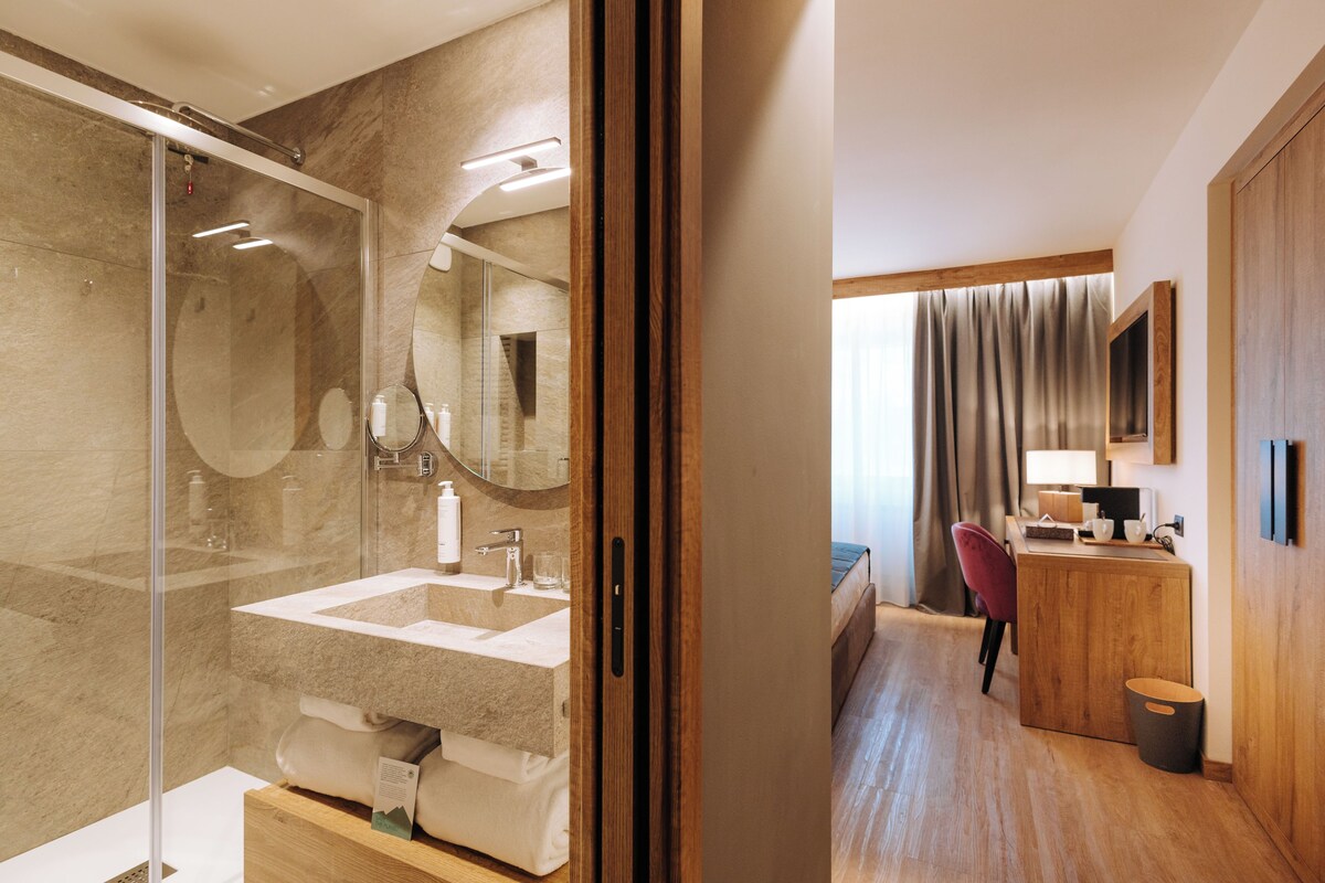 A modern bathroom with a glass shower enclosure, a wooden vanity, and a large mirror.