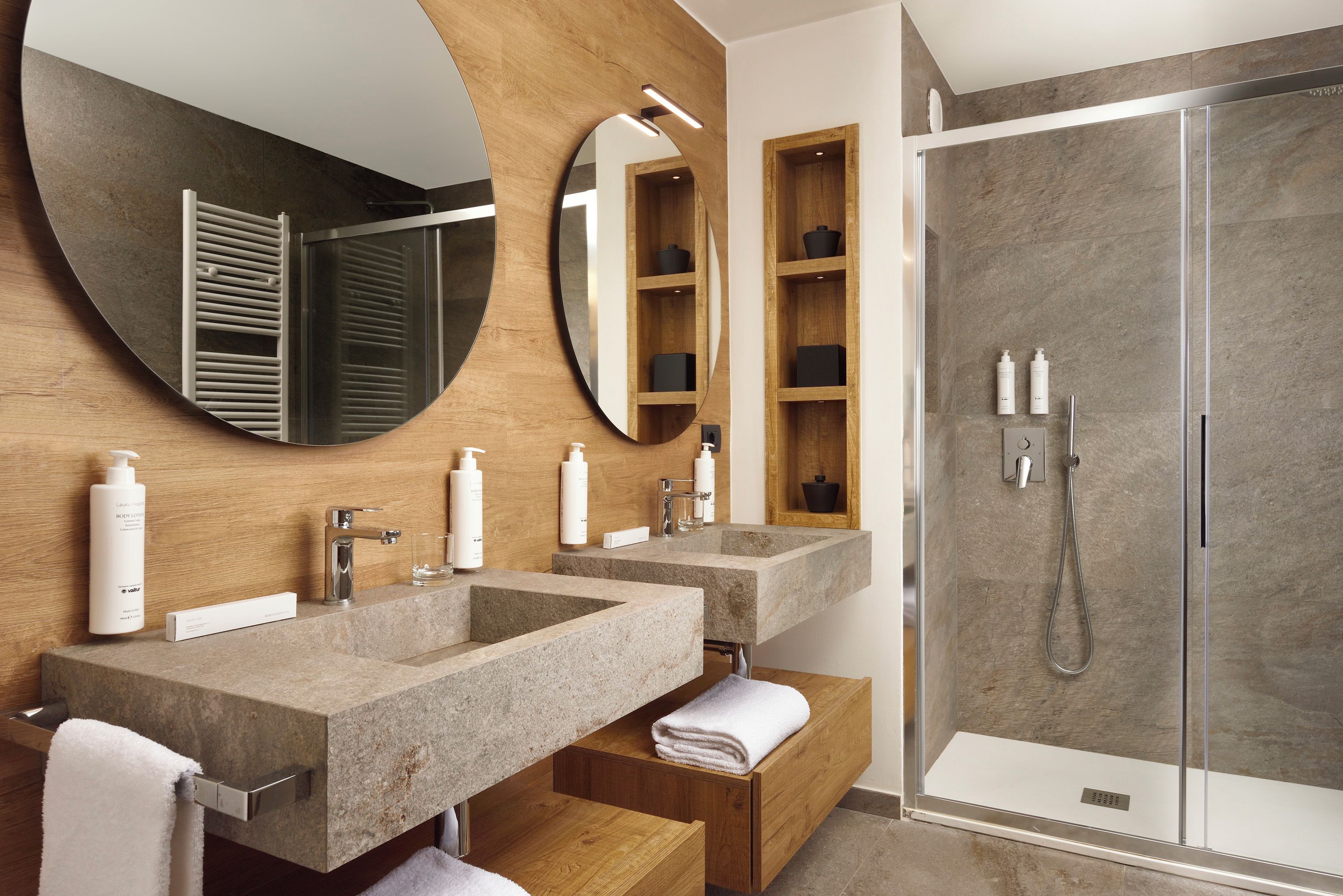 Un baño moderno con dos lavamanos, un espejo grande y una ducha a ras de suelo.