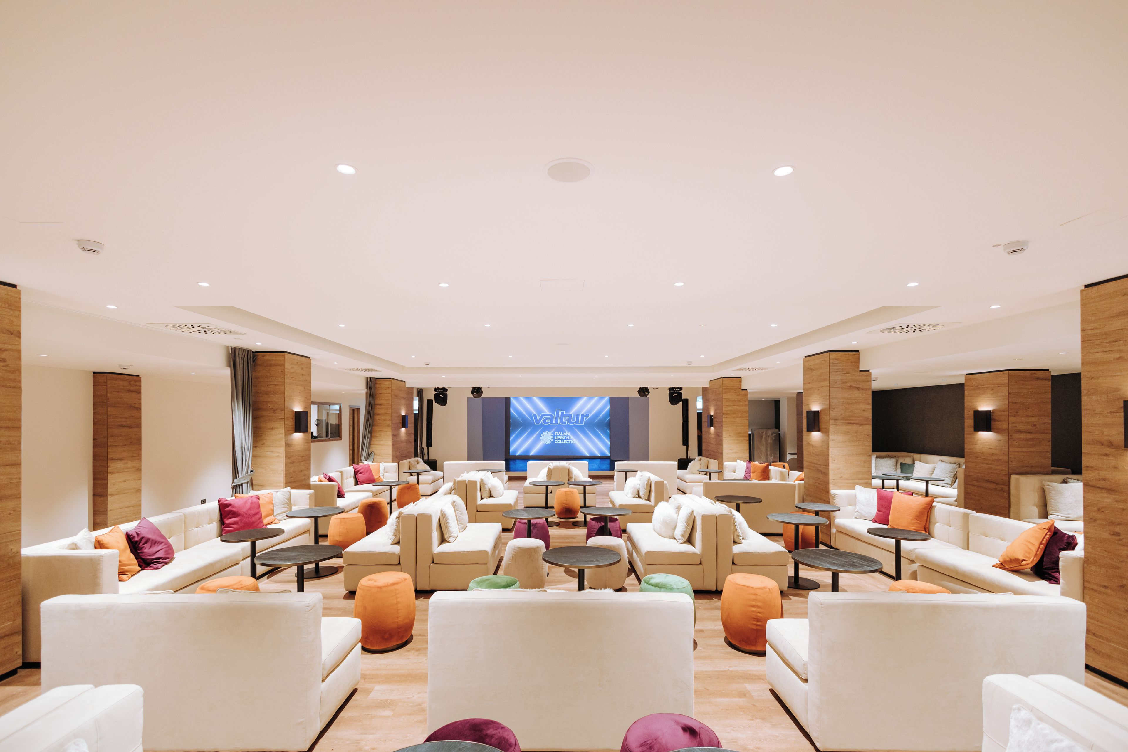 A spacious lounge area with multiple seating options, a large screen, and a modern design.