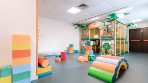 Ein Spielbereich mit bunten Schaumstoffbausteinen, einem Spielhäuschen und weichen Spielgeräten.