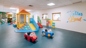 Un espace de jeux pour enfants avec un toboggan, un mur d’escalade et des structures de jeu colorées.