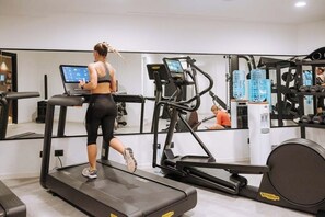 Ein Fitnessstudio mit Laufbändern, Kraftgeräten und einer Spiegelwand.