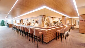 Un espace bar moderne doté d’un long comptoir, de plusieurs tabourets et d’un élément décoratif central.