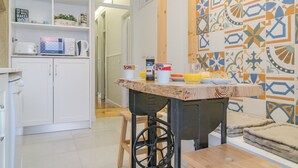 A kitchen with white cabinets, a microwave, a coffee maker, and a table with a wooden top.