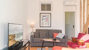 A living room with a grey sofa, a red armchair, a coffee table, and a flat-screen TV.