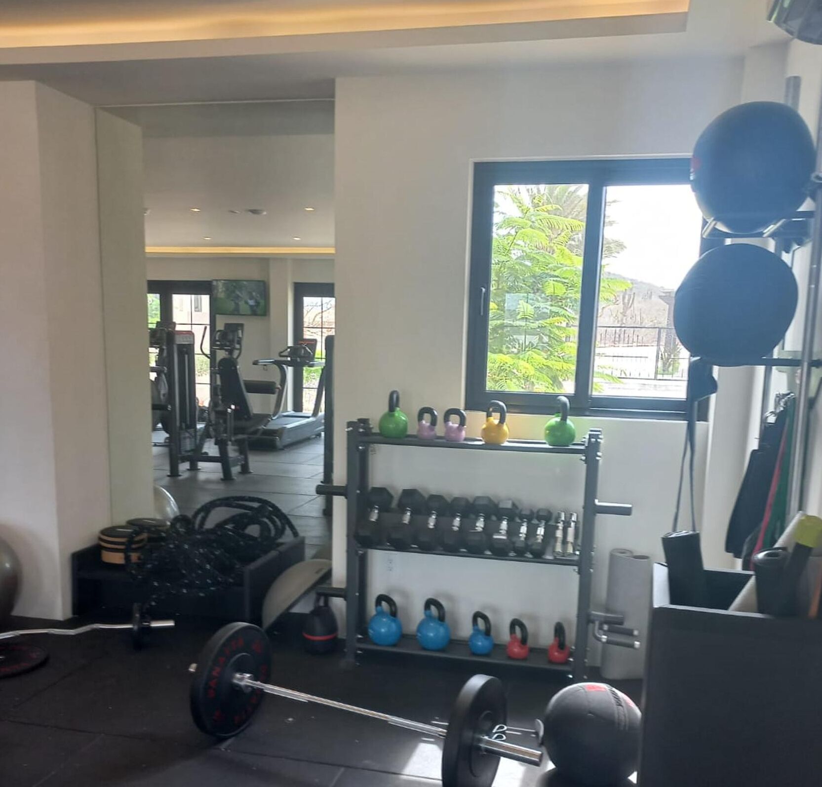A gym with weightlifting equipment, treadmills, and kettlebells.