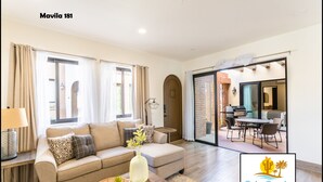 A spacious living room with a sofa, coffee table, and a dining area with chairs and a table.