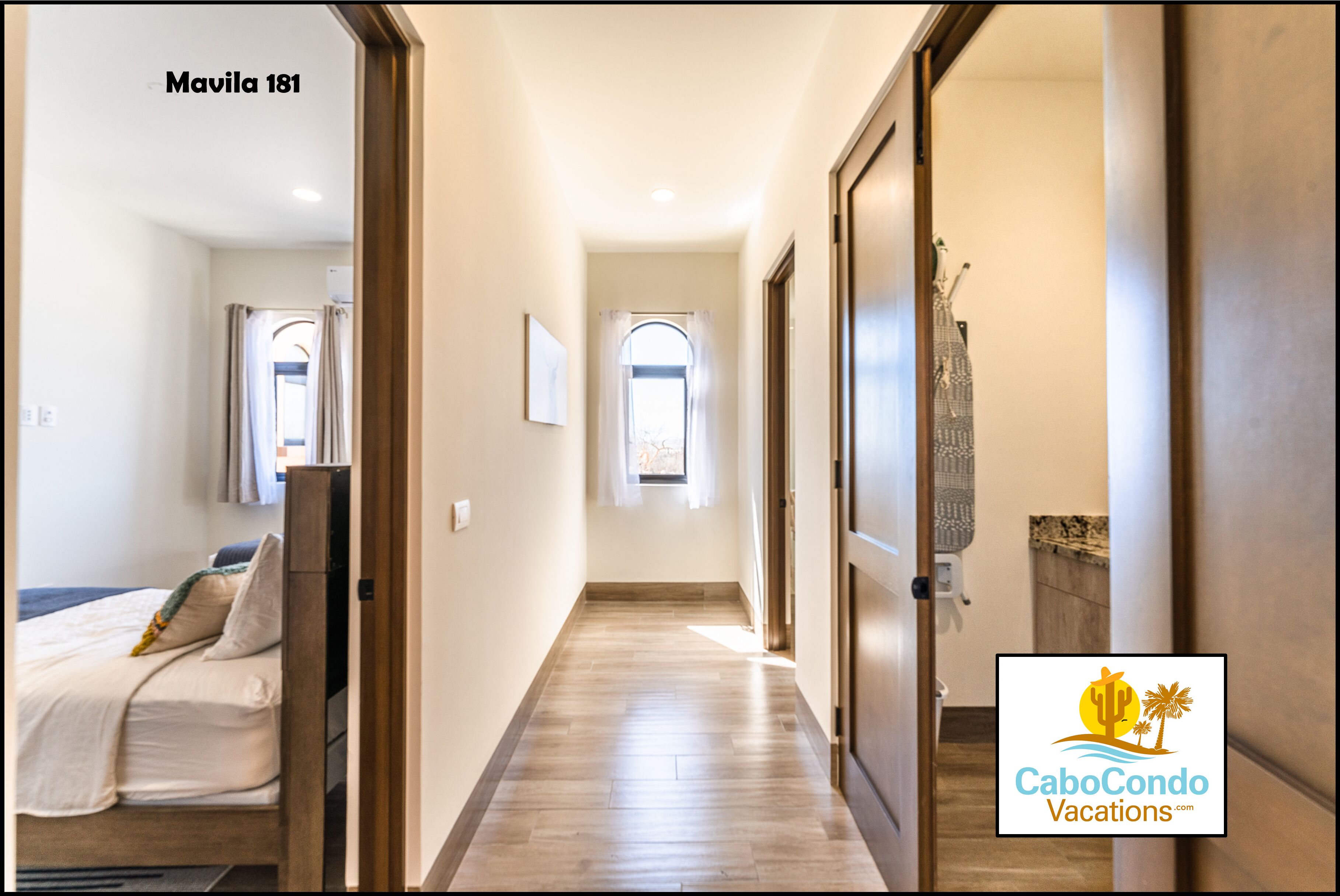 A hallway with a bed on the left, a window, and a door on the right.