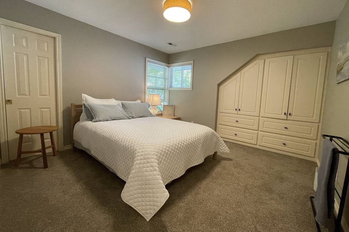 A bedroom with a bed, a nightstand, a chair, and a wardrobe.