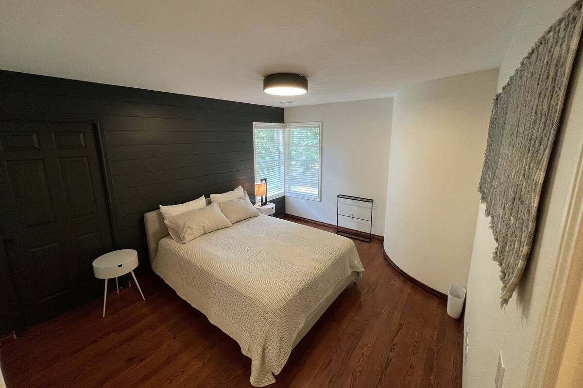A bedroom with a bed, a nightstand, a window, and a door.