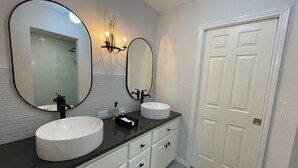 A bathroom with two sinks, a large mirror, and a white door. - The Gaard House (Carlton)
