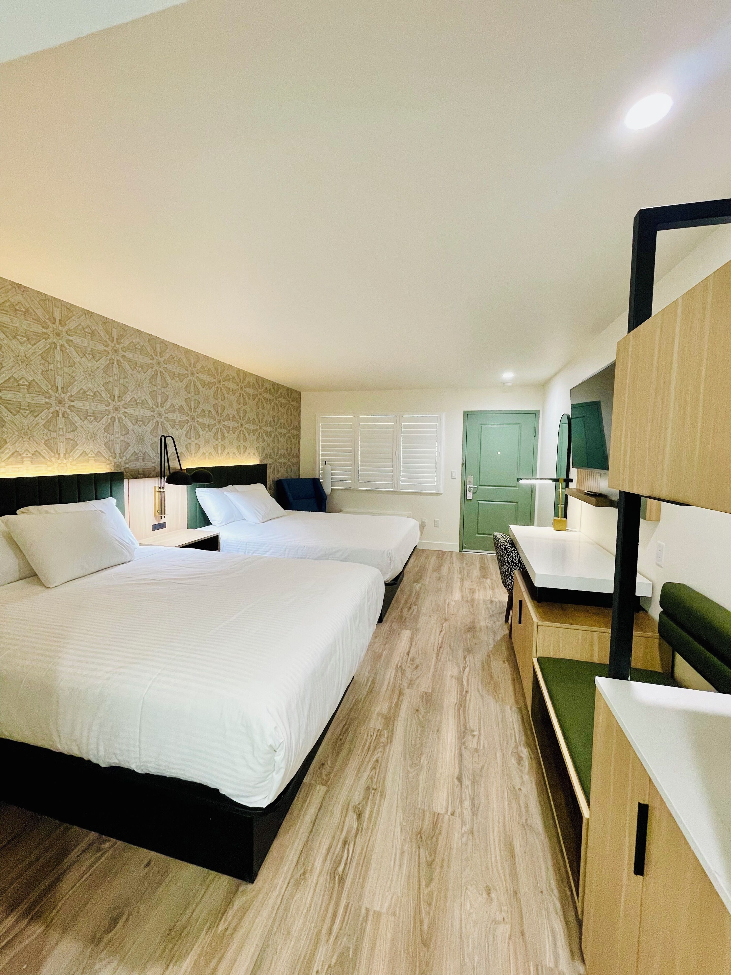 Une chambre d’hôtel avec deux lits, un bureau et une chaise verte.