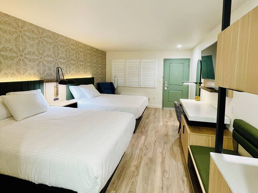 Une chambre d’hôtel avec deux lits, un bureau et une chaise verte.