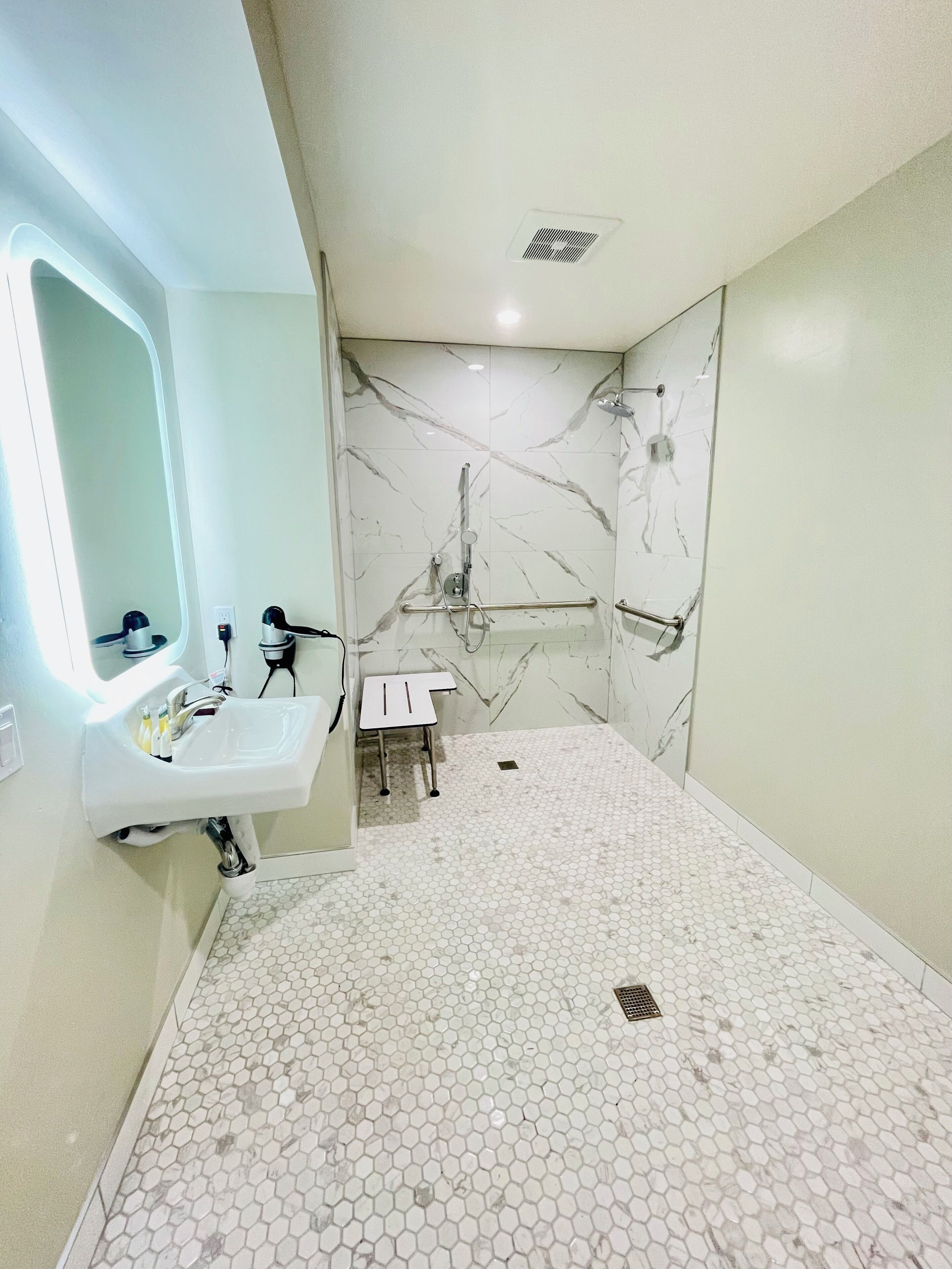 Une salle de bain équipée d’un lavabo, d’un miroir et d’un espace douche.