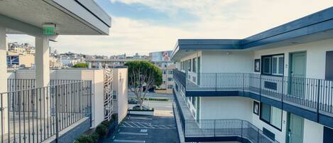 A multi-story building with balconies, a parking area, and a clear sky.
