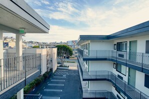 Ein mehrstöckiges Gebäude mit Balkonen, einem Parkplatz und blauem Himmel.