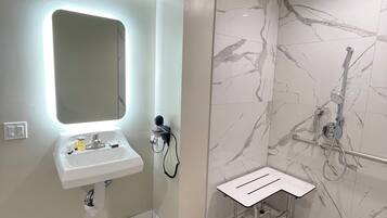 Ein modernes Badezimmer mit integriertem Waschbecken, einem Spiegel und einer Duschkabine.