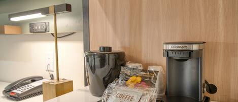 Une petite cuisine équipée d’une machine à café, d’une bouilloire, d’un distributeur de capsules de café et d’un téléphone posé sur un comptoir.