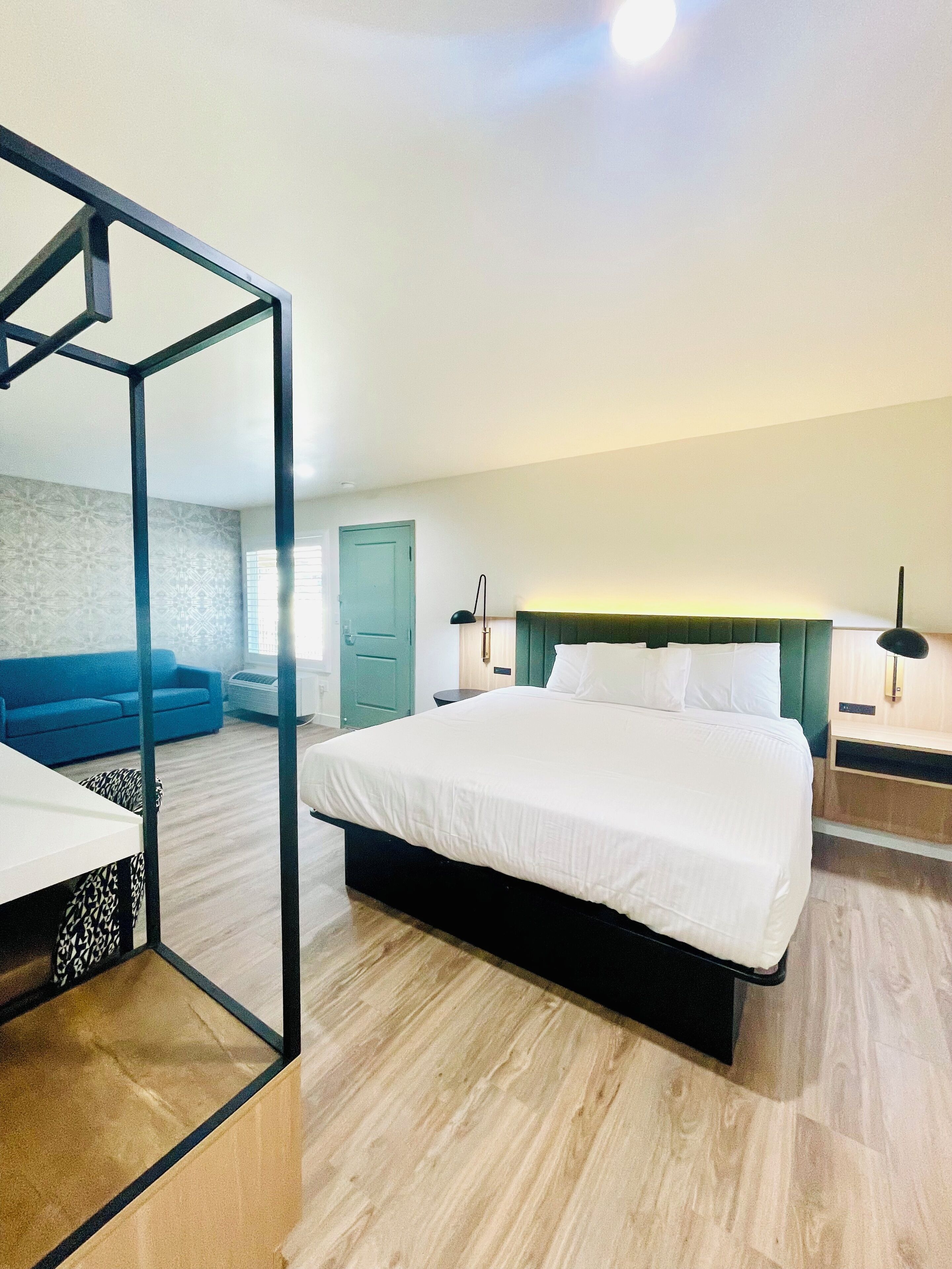 Un dormitorio moderno con una cama grande, un sofá azul y un armario con espejo.