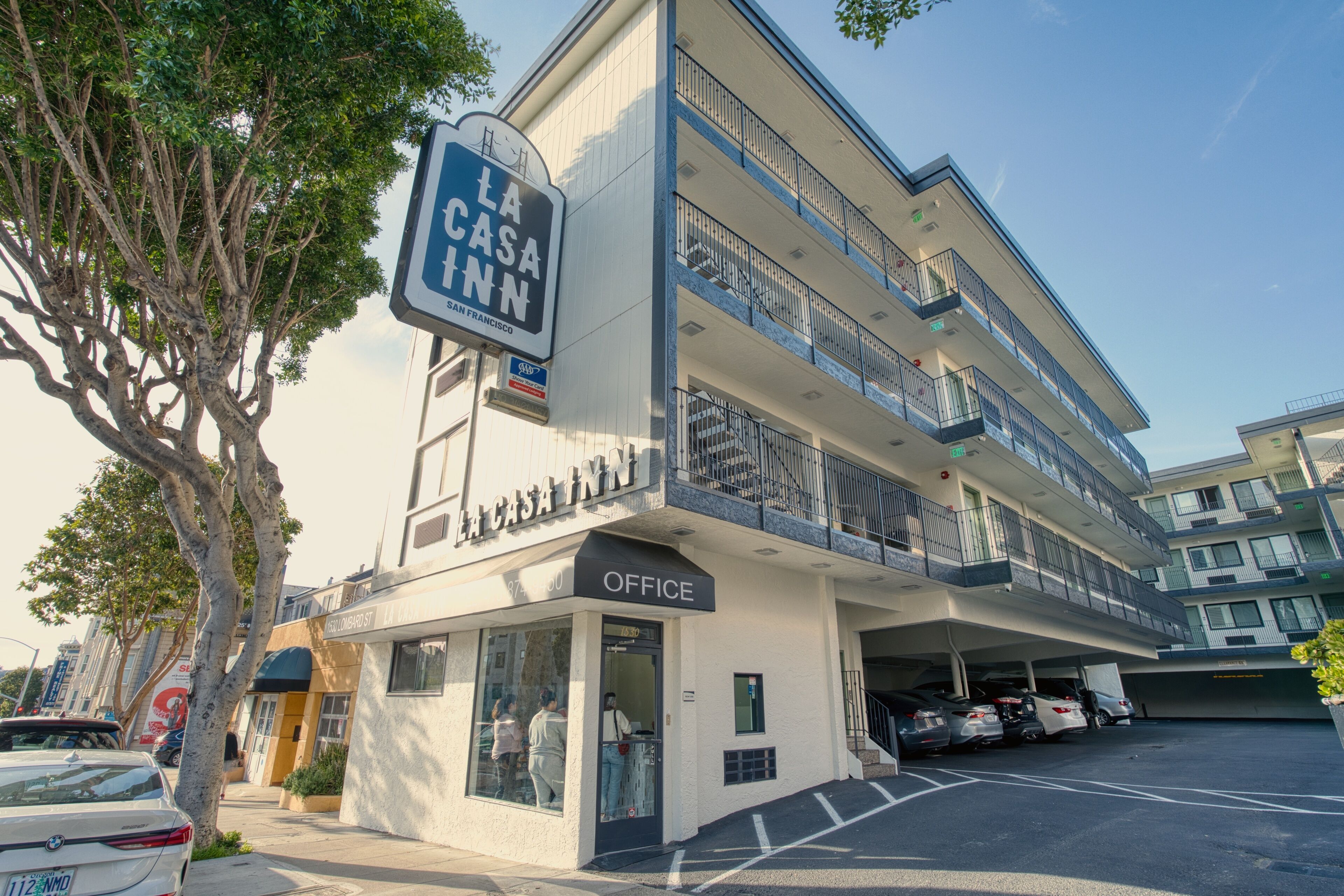 A multi-story building with a sign for La Casa Inn, featuring a ground-level office and parking area.