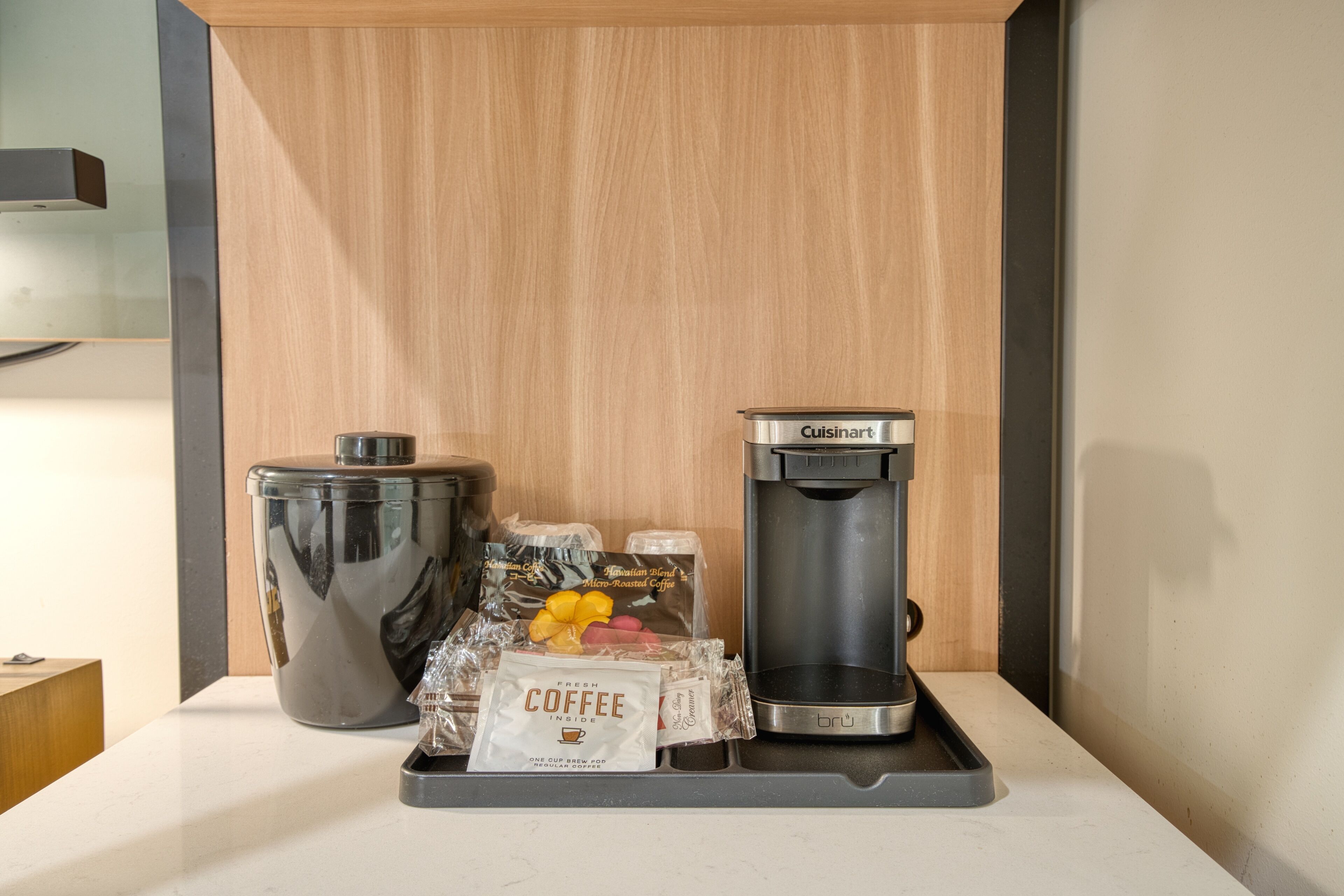 A coffee station with a coffee maker, a grinder, and coffee pods on a countertop.
