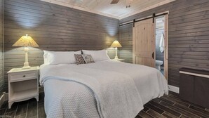 Ein Schlafzimmer mit einem Bett, zwei Nachttischen mit Lampen, einem Deckenventilator und einer Schiebetür.