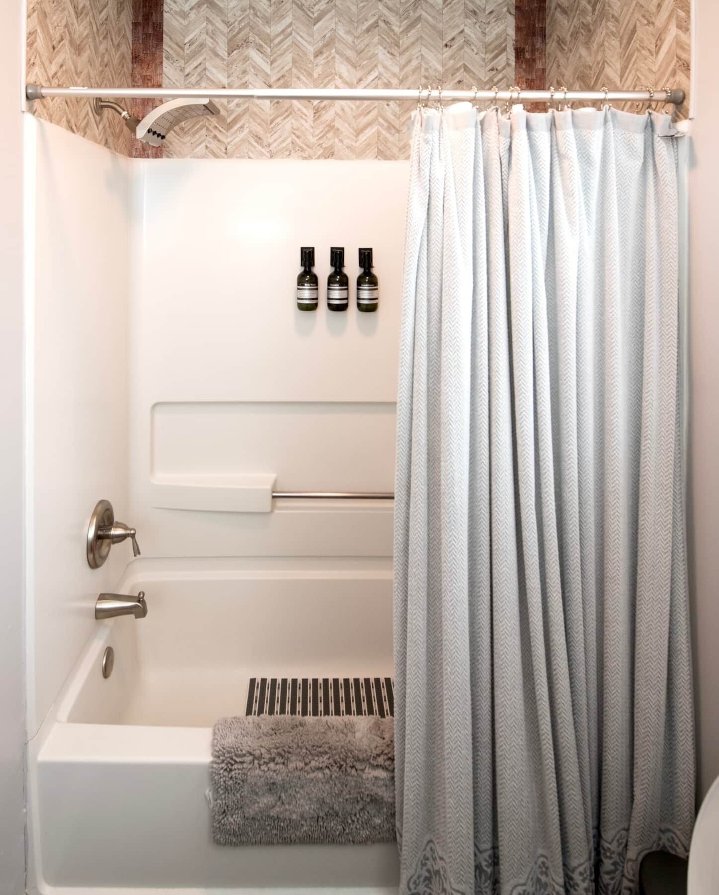 A modern bathroom with a bathtub, a shower, and a towel rack.