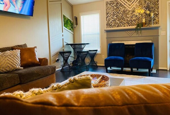 Ein Wohnzimmer mit einer Couch, zwei Sesseln, einem Kamin und einem Fernseher.