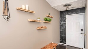 A hallway with a wooden bench, a blackboard with chalk writing, and a white door. - The Herringbone Blue (Harnett County)