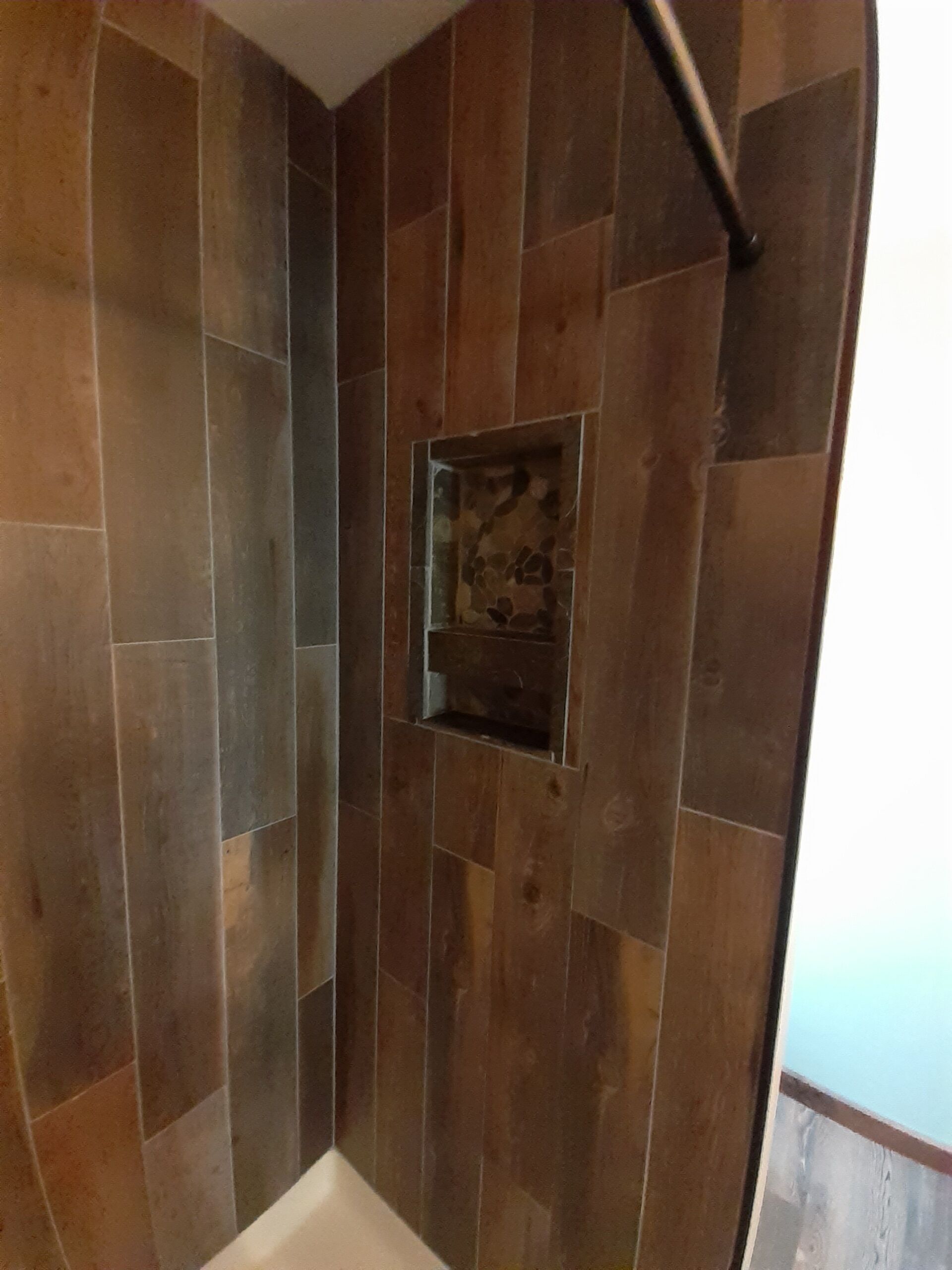 A shower with a stone wall and a small window.
