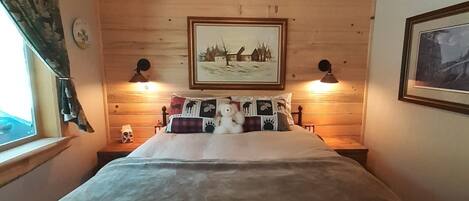 A bedroom with a bed, a ceiling fan, two wall-mounted lamps, and a framed picture on the wall.