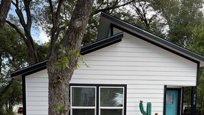 A small, single-story house with a white exterior and black trim. - New Lovely Lockhart Home with a Lawn (Lockhart)