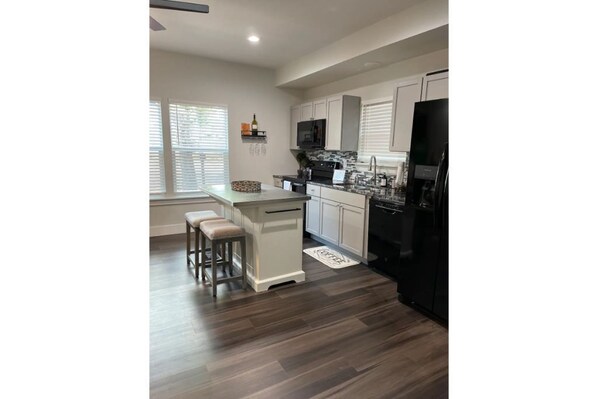 Enjoy cooking in this well-lit kitchen with a central island, microwave, and large refrigerator.